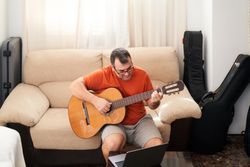 a man relaxing on the couch playing guitar