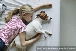 Young girl lying on bed with her dog with their eyes open 5lVe6b