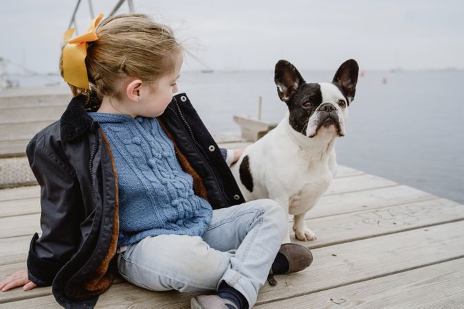 young girl with dog on pier