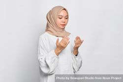 Calm Muslim woman in headscarf and light blouse with hands up in prayer 5new20