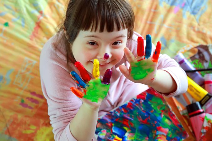 Happy young girl playing with finger paints