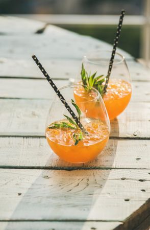 Orange cocktails in glass with garnish, and eco-friendly straws
