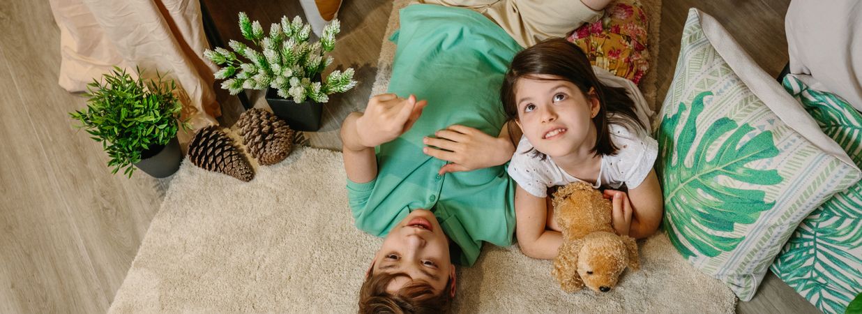 Banner of boy pointing with finger up and smiling little girl looking while embracing stuffed dog.