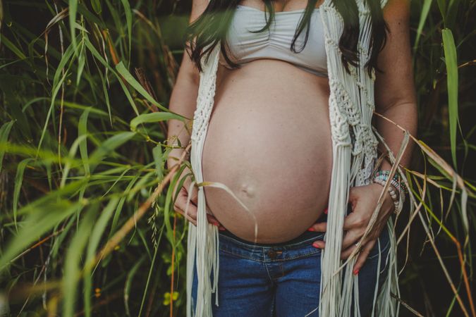 Pregnant woman touching belly in park