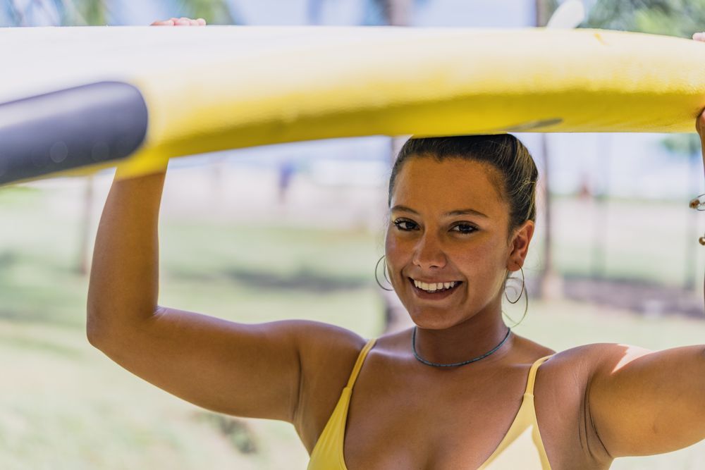 Woman in bikini with bright paddleboard on beach