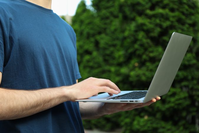 Young man in t-shirt holding laptop outdoor. Study. University