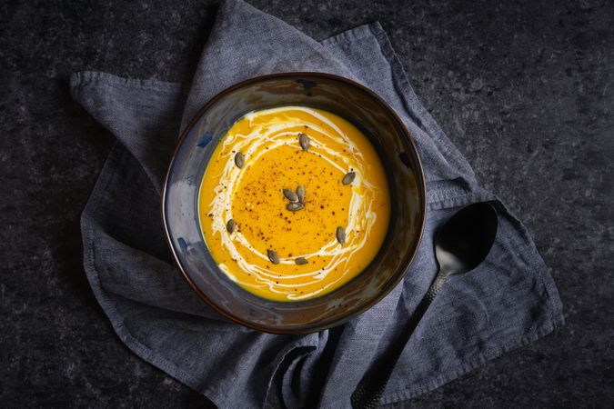 Bowl with pumpkin puree soup on table