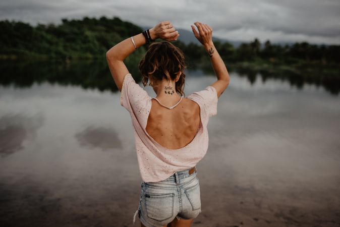 Anonymous female standing towards sea on sunset