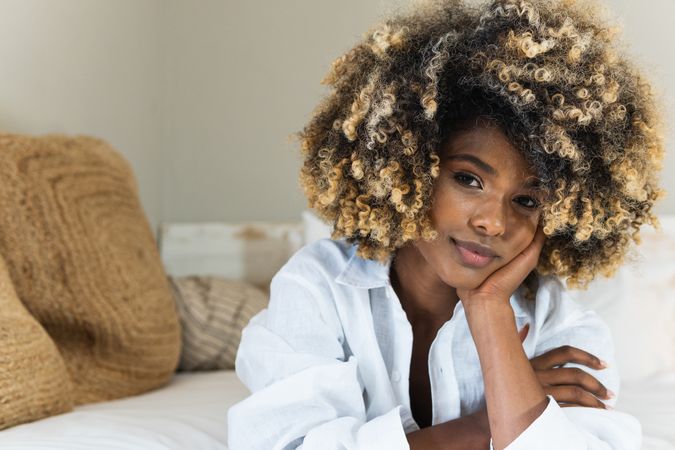 Thoughtful Black woman lying on bed in bedroom