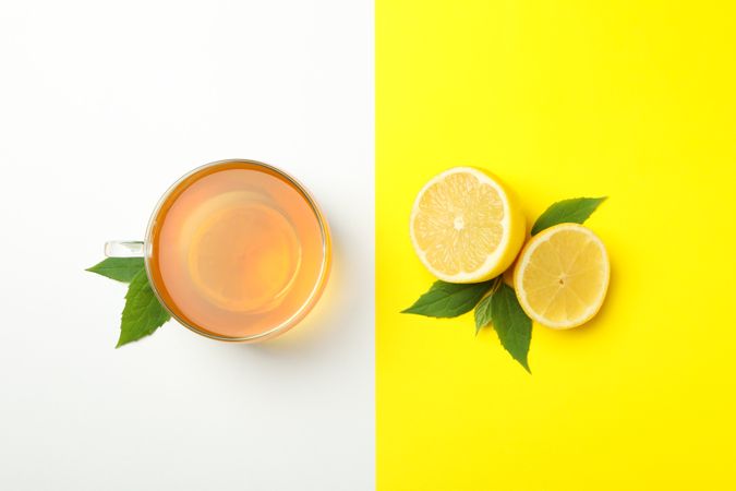 Tea and lemon on two tone background, top view. Ripe fruit
