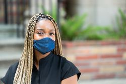 Portrait of medical worker wearing mask smiling and looking at camera outside