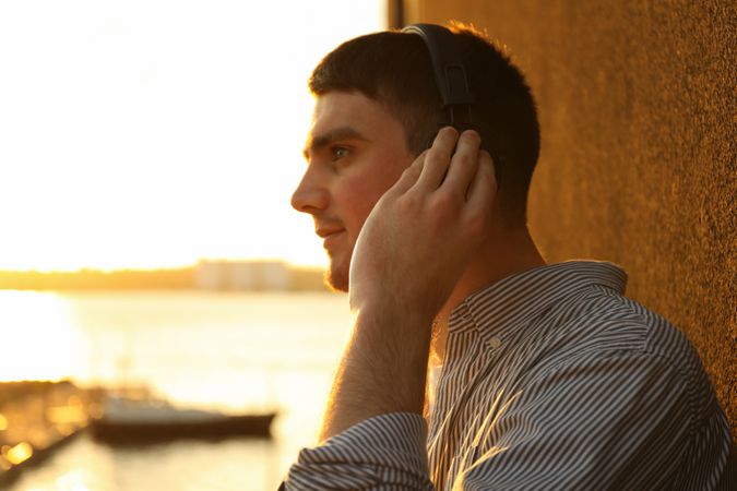 Young man in headphones listen music. Amazing sunset