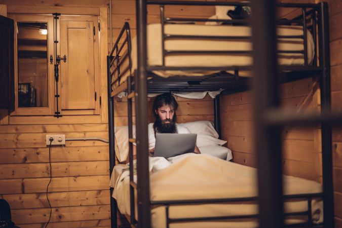 Man using laptop in rustic bunk bed