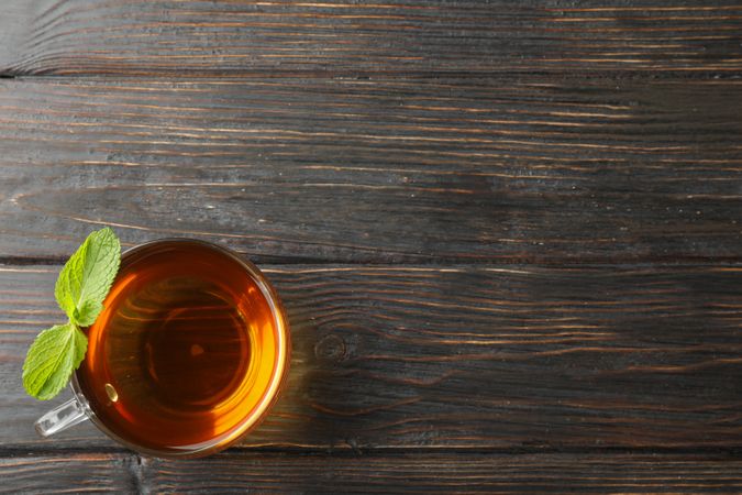 Cup of tea with mint on wooden background, top view