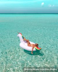 Woman in bathing suit lying on an inflatable unicorn floating on sea surface  during daytime bE8a74