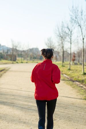 Back of woman jogging outdoors on sunny day