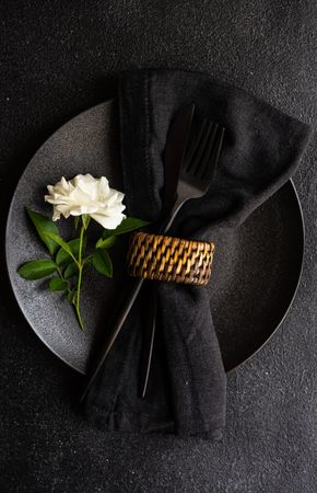Minimalistic table setting with rose on plate with napkin