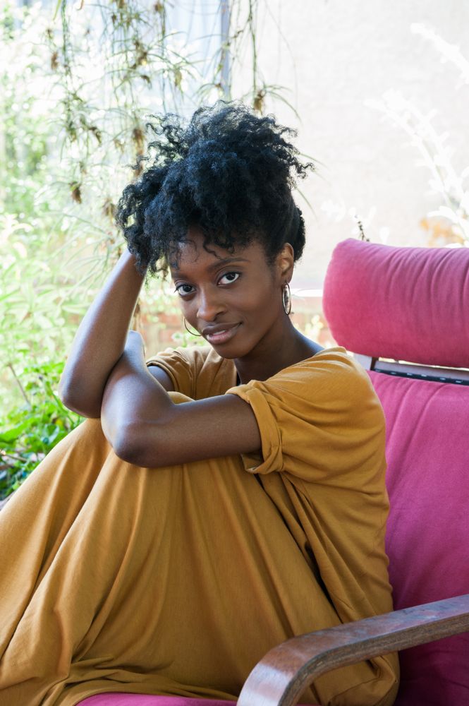 Woman with curly bun looking at camera confidently while sitting outside