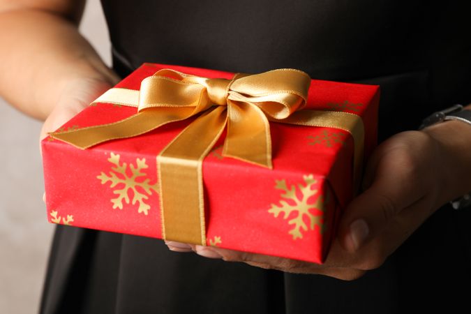 Young woman holding gift box with bow, close up
