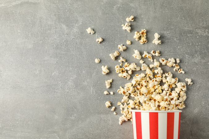 Flat lay composition with bucket and popcorn on grey background, copy space