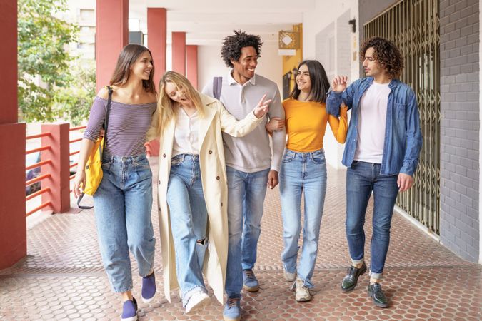 Group of friends strolling down the street outside and goofing around