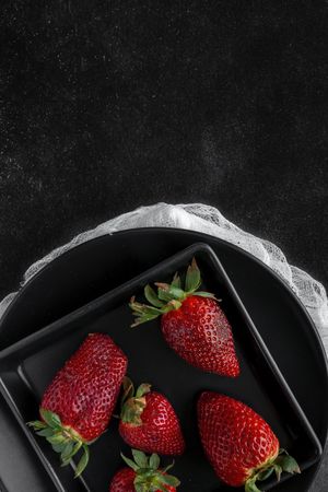 Red and fresh strawberries flat lay in dark dish