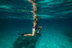 Boy in flippers swimming underwater in sea