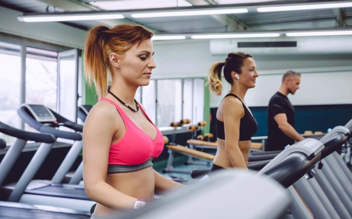 Fit men and women doing cardio on treadmills in gym