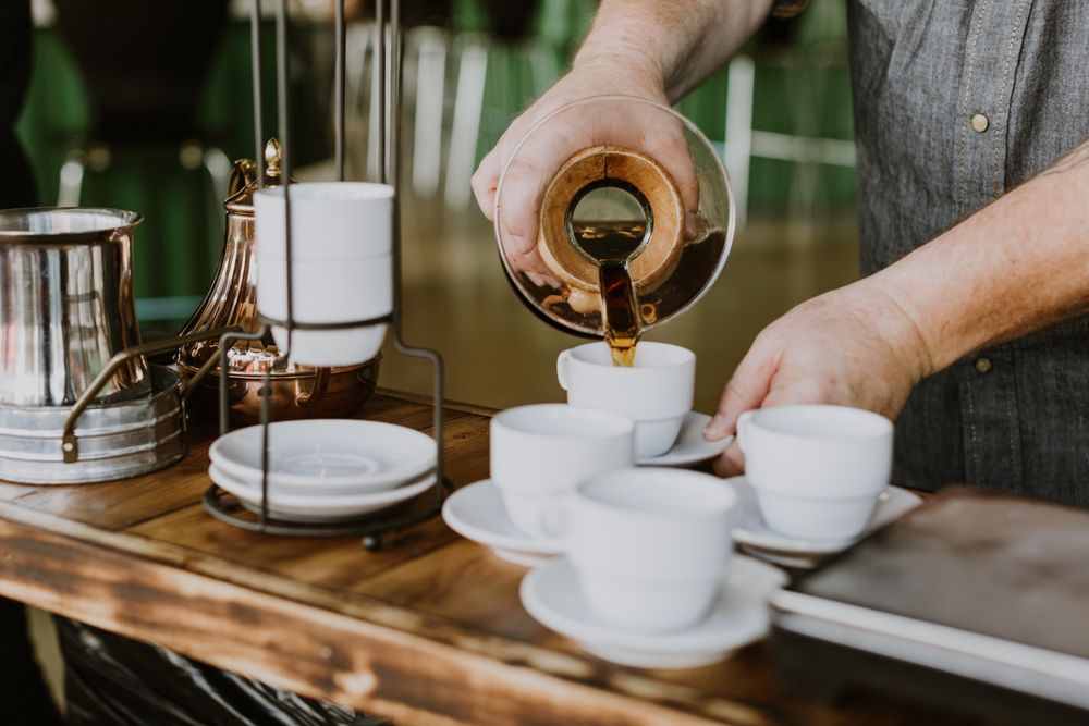 Person pouring coffee into ceramic cups
