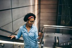 Woman smiling looking at phone on escalator