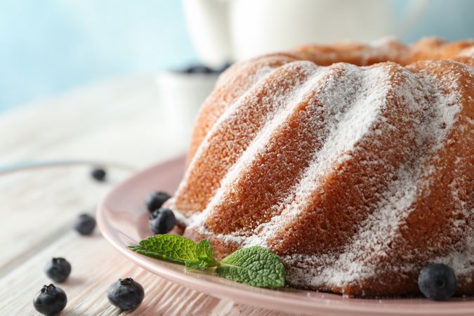 Cake with powder sugar and blueberry on wooden background, space for text