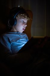 Boy playing on tablet at night time