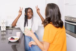 Two women talking with hand gestures over coffee in the kitchen
