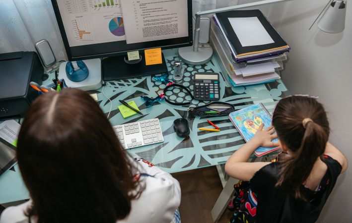 Woman teleworking with her daughter drawing