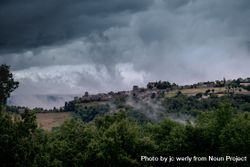 Low clouds over a French village surrounded by green bushes 5RzQO5