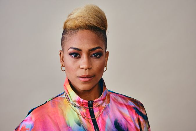 Studio shot of Black woman in bold 80s windbreaker jacket and gold jewelry with copy space