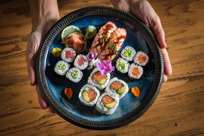 Person with plate with assorted sushi