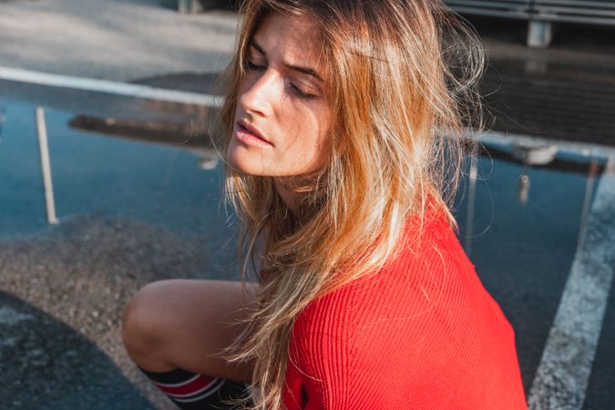 Charming woman in sweater on street between puddles