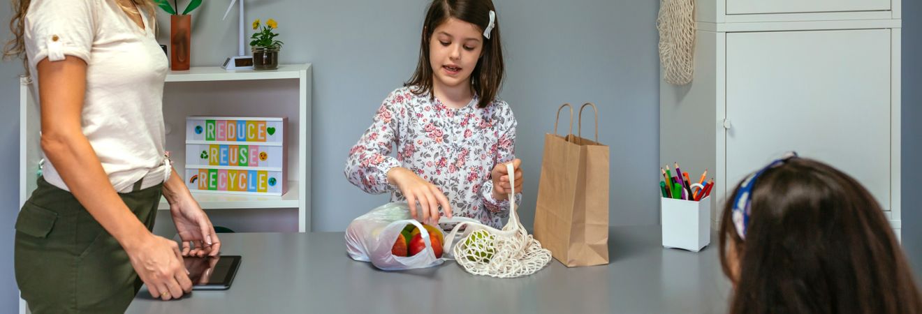 Student showing reusable mesh shopping bag in ecology classroom
