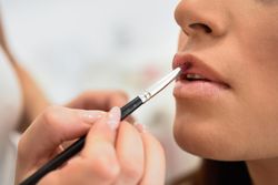 Woman having lipstick applied by a professional