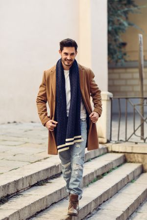 Smiling man wearing winter clothes on outdoor stairs