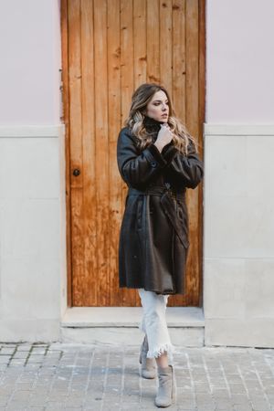 Stylish woman standing near brown door
