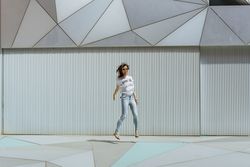 Cheerful woman jumping near modern wall