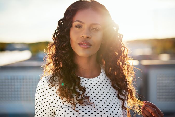 Beautiful Black woman playing with hair on sunny roof top