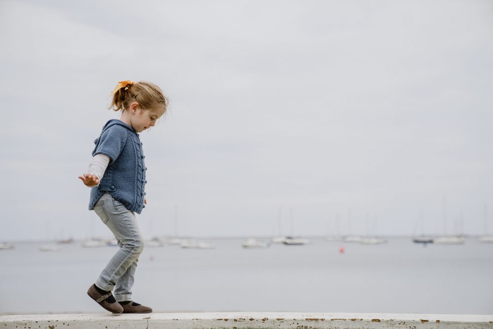 Girl balancing on border near sea