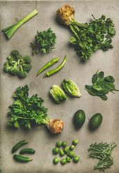 Arrangement of fresh green garden vegetables on concrete surface