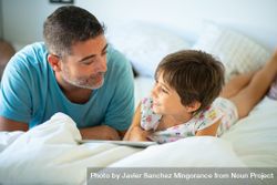 Dad with child playing on tablet in bed 4mJpvb