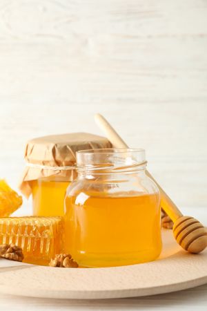 Honeycombs, walnuts, dipper and jars with honey on wooden background, copy space