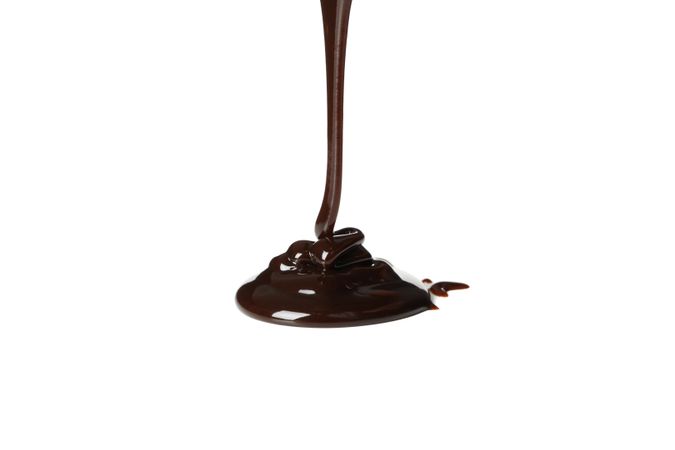 Melted chocolate is pouring, isolated on blank background