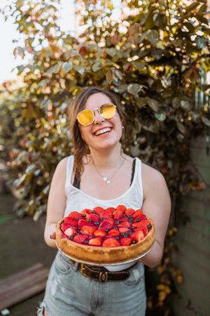 cheerful woman holding a delicious strawberry pie
